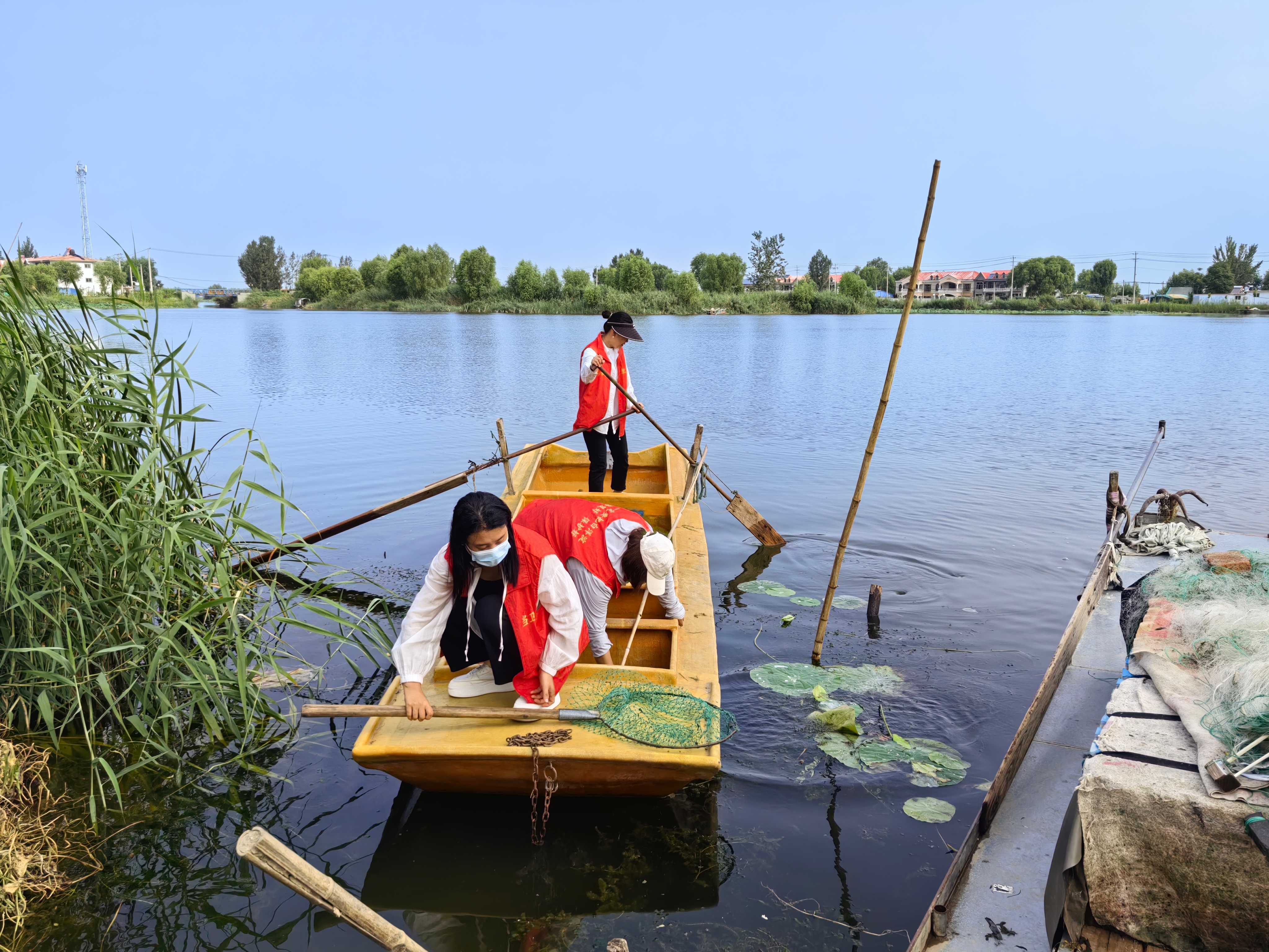 　　“水生嫂”志愿服务队的队员们在淀边清理垃圾。新华社发