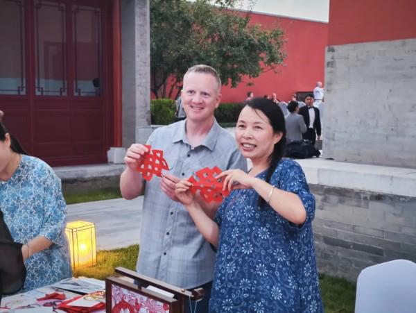 嘉宾体验非遗剪纸，与指导老师合影留念。